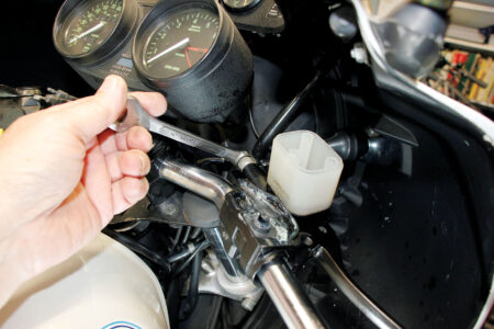 A hand loosening the banjo fitting